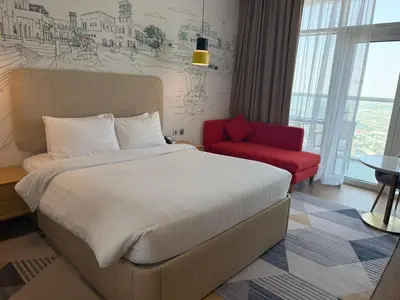 a bedroom with a large bed and a red chair at Luxery Hotel Apartment l Novotel Residence l JVT in Dubai