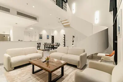 a living room with white furniture and a table at FIRST CLASS 2BR Elegant Duplex Haven in Dubai
