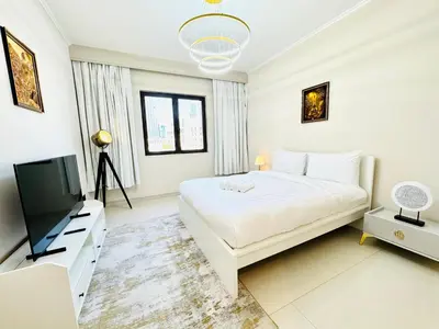 a white bedroom with a bed and a flat screen tv at Burj Khalifa View 2 Bed Luxury Apartment in Dubai