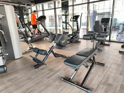 a gym with cardio equipment and a man in an orange shirt at Cozy Modern 1BR with Dubai Skyline View in Dubai