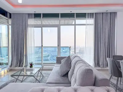 a living room with a large couch and large windows at Opal Tower Condos - Dubai Marina in Dubai