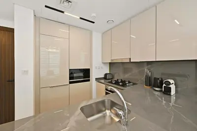a kitchen with white cabinets and a stainless steel counter top at New, Bright & Cozy 1BD at Paragon by IGO, Dubai in Dubai