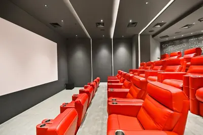 an empty lecture room with red seats and a chalkboard at New, Bright & Cozy 1BD at Paragon by IGO, Dubai in Dubai