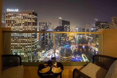 two people taking a picture of a city skyline at night at Frank Porter - Marina Mall Hotel in Dubai