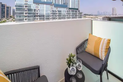 a balcony with a chair and a table with wine glasses at Frank Porter - Azizi Riviera 51, Meydan in Dubai