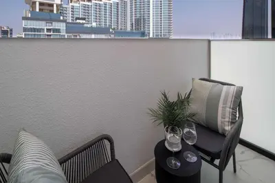 a balcony with two chairs and a table with wine glasses at Frank Porter - Azizi Riviera Azure, Meydan in Dubai
