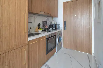 a kitchen with wooden cabinets and a stove and a dishwasher at Frank Porter - Azizi Riviera Azure, Meydan in Dubai