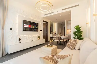a living room with a white couch and a tv at Premium 1BR Stay with Balcony & City View, Nad Al Sheba in Dubai