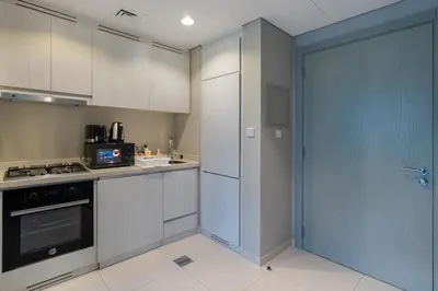 a kitchen with white cabinets and a blue door at Zada Tower, Business Bay - 1 Bedroom - Allsopp & Allsopp in Dubai