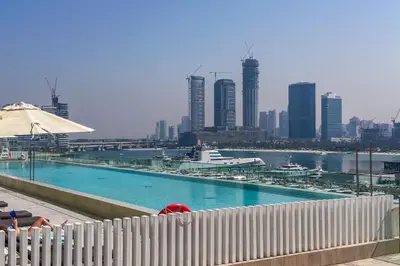 a large swimming pool with a city in the background at Luxury 3BR plus Maids Room in Emaar Beachfront in Dubai