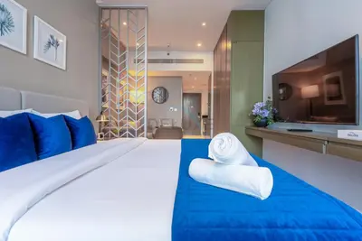 a hotel room with a large bed with blue sheets and a television at Full Canal Views, Minutes from Downtown and Burj Khalifa, Close to Metro Station - Prive By Damac B, Business Bay by Deluxe Holiday Homes in Dubai