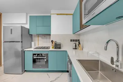 a kitchen with white counters and blue cabinets at Opal by Danube | Designer 1BR | Private Jacuzz in Dubai