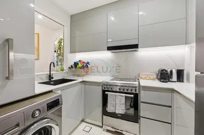 a white kitchen with a sink and a dishwasher at Creek Harbour Views 1BR, Just Minutes from Ras Al Khor Wildlife Sanctuary and Short Stroll to Zabeel Stadium, Binghatti Creek, Al Jaddaf by Deluxe Holiday Homes in Dubai