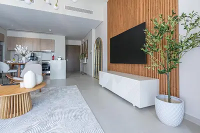 a kitchen and living room with a tv on a wall at Nasma Luxury stays- Luxury-highfloor-iconic location in Dubai