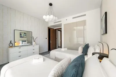 a white bedroom with two beds and a mirror at FIRST CLASS 3BR Stylish Luxury Escape in Dubai