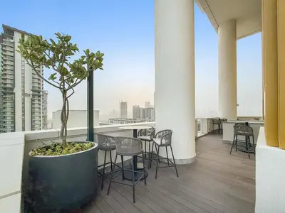 a balcony with chairs and a potted tree on a building at FIRST CLASS 3BR Trendy Luxe Getaway in Dubai