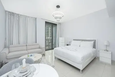 a white bedroom with a bed and a couch and a table at Urban Skyline Haven Near Burj Khalifa in Dubai