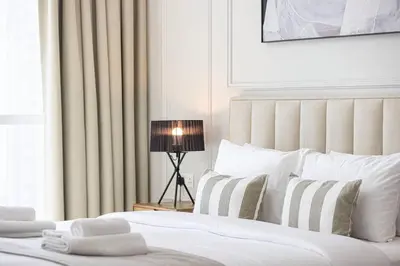 a bedroom with a bed with white sheets and a lamp at StayMada - Torch Tower Marina Walk Gym and Sauna in Dubai