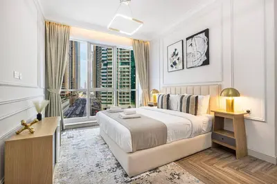 a white bedroom with a bed and a large window at StayMada - Torch Tower Elegant Marina Retreat in Dubai
