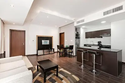 a living room with a couch and a kitchen at Comfy 1BR apartment in Sport City in Dubai