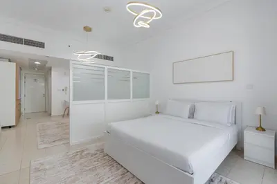 a white bedroom with a white bed and a tv at Vacay Lettings - Lake Terrace JLT - Walk to Metro in Dubai