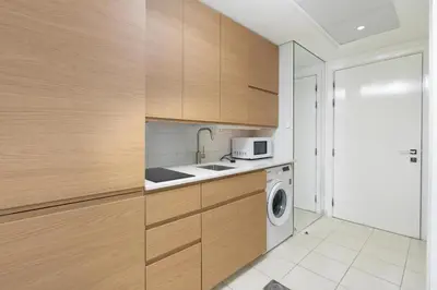 a kitchen with wooden cabinets and a washing machine at Vacay Lettings - Lake Terrace JLT - Walk to Metro in Dubai