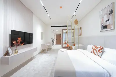 a white bedroom with a large bed and a tv at Premium Stay at High-Floor Trillionaire Studio in Dubai