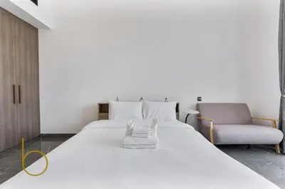 a bedroom with a large white bed and a couch at Bookable Studio Room Joya Blanca,Arjan with Tennis court access in Dubai