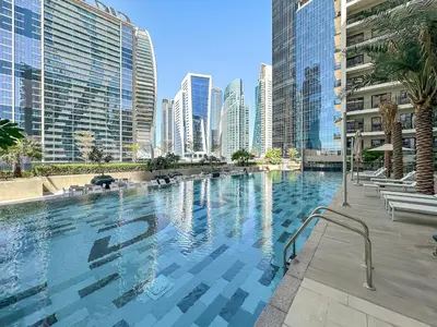 a large swimming pool in a city with tall buildings at FIRST CLASS 1BR Pool View & Prime Location in Dubai