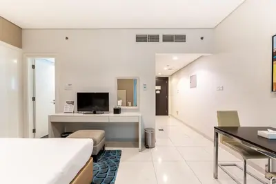 a room with a bed and a desk with a television at HAVN - Studio in Cour Jardin, Business Bay in Dubai