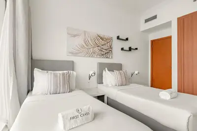 two beds in a room with white walls at FIRST CLASS 2BR Breathtaking Marina Views in Dubai