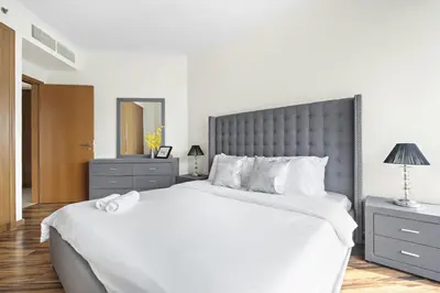 a bedroom with a large white bed with a gray headboard at VayK - Spacious 2BR in JLT with Marina Views in Dubai