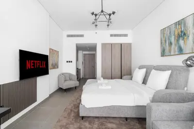 a bedroom with a bed and a tv and two chairs at VayK - Modern Studio with Great Amenities in Dubai