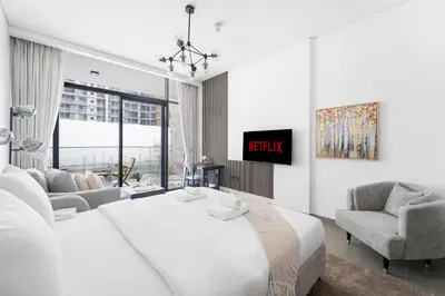 a bedroom with a large white bed and a tv at VayK - Modern Studio with Great Amenities in Dubai