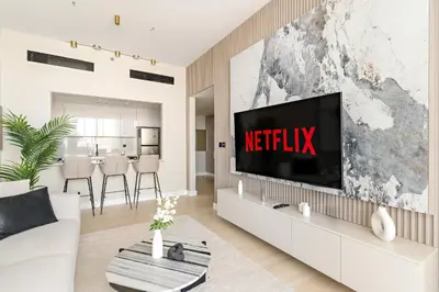 a living room with a television on a wall at VayK - Luxurious 2BR in JVC in Dubai