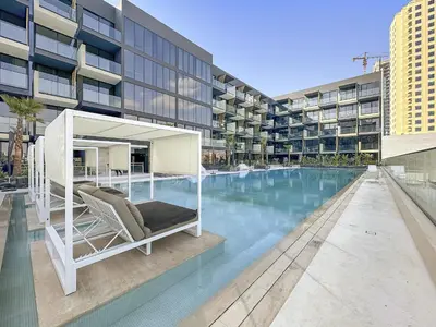 a hotel swimming pool with a chair next to a building at VayK - Luxurious 2BR in JVC in Dubai