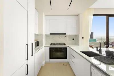 a kitchen with white cabinets and a stove top oven at VayK - Stylish 2BR in JVC with Private Pool in Dubai