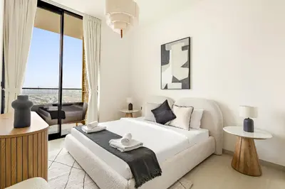 a white bedroom with a bed and a living room at VayK - Stylish 2BR in JVC with Private Pool in Dubai