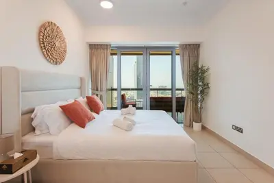 a bedroom with a large white bed with a window at Bright 2BR with Burj, Sea & City Views - Walk to Mall in Dubai