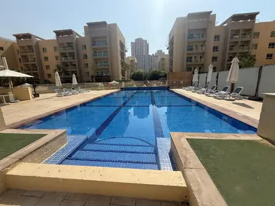 a large swimming pool with chairs and umbrellas at HAVN - Studio in Alka, The Greens in Dubai