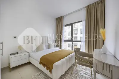 a bedroom with a bed and a desk and a window at Bloomfields Cozy 1br Apt Town Square in Dubai