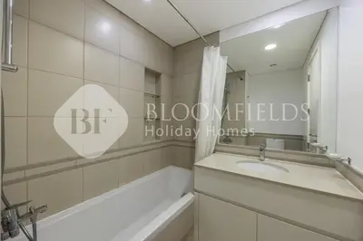 a bathroom with a tub and a sink and a mirror at Bloomfields Cozy 1br Apt Town Square in Dubai