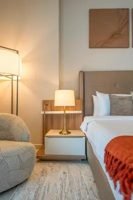 a bedroom with a bed and a lamp and a chair at Chic 1 Bedroom in Business Bay in Dubai
