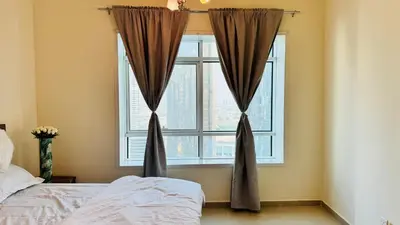 a bedroom with a bed and a large window at Beautiful 1 Bedroom Apartment close to metro in Dubai