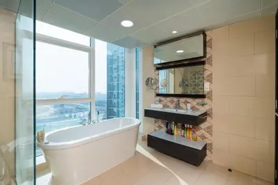 a bathroom with a tub and a large window at Comfortable - Vibrant - Convenient in Dubai
