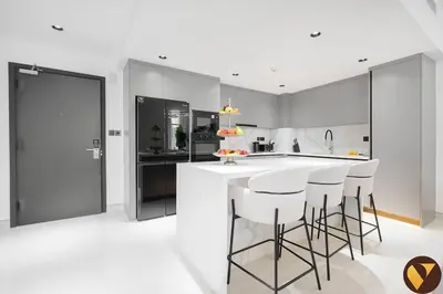 a kitchen with a white counter and bar stools at Vogue Marina Dorra Bay near JBR Beach and Ain Dubai, Two Bedroom apartment with Balcony, Canal and Skyline View, Access to all Amenities in Dubai