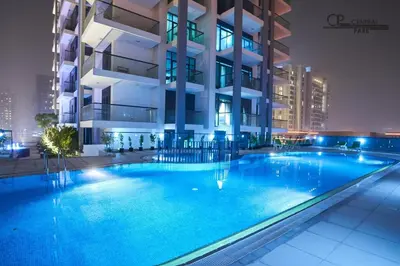 a swimming pool in front of a building at night at Mahenti - Spacious 1-Bedroom Apartment in JVC in Dubai