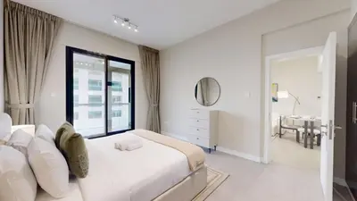 a white bedroom with a large bed and a table at Locations l Upgraded 1 Bedroom l Marina Views l Free Pool Access in Dubai