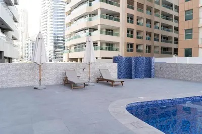 a patio with chairs and umbrellas next to a pool at Locations l Upgraded 1 Bedroom l Marina Views l Free Pool Access in Dubai