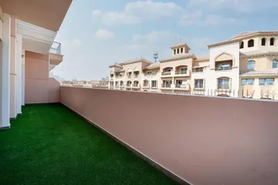 a balcony of a building with green grass at Elegant JVC 1-Bed with Upgraded Interiors in Dubai